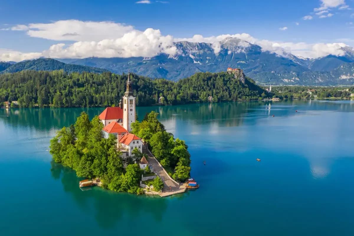 Church on island in Lake Bled with Julian Alps and castle on hill background