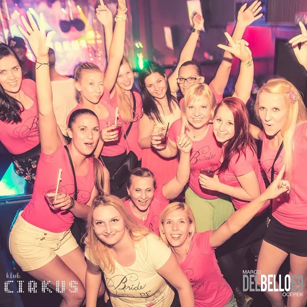 Group of women celebrating in a nightclub, many wearing pink "Bride" shirts, Ljubljana.